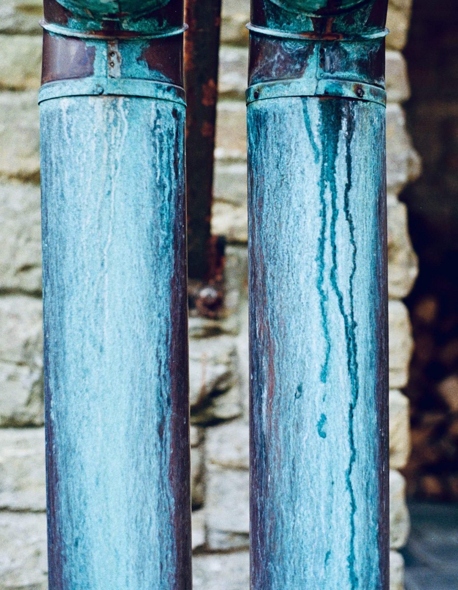 Two old metal pipes streaked with blue-green corrosion