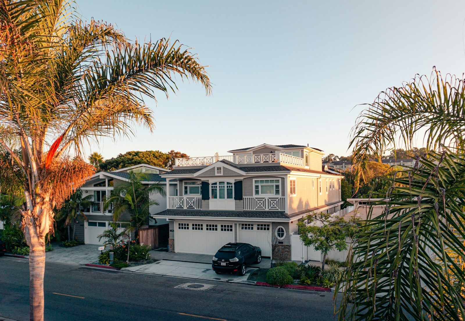 Two-story house with a garage, framed by palm trees